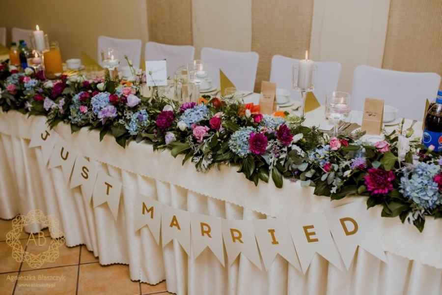 Podłużna dekoracja stołu pary młodej girlanda z zieleni fioletowe i niebieskie kwiaty róże hortensje dalie abkwiaty Kraków