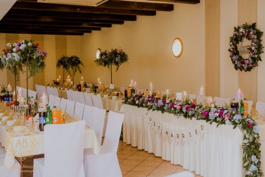 Dekoracja sali weselnej kompozycje kwiatowe na stołach niebieskie i foletowe kwiaty podłużne kompozycje wysokie abkwiaty Kraków