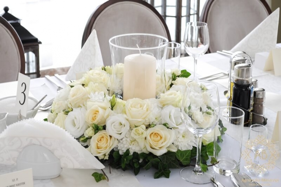 Wianek z białych i kremowych kwiatów ze świecą w szkle w środku