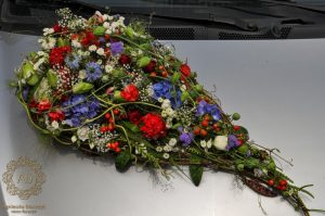 Dekoracja samochodu podłużna kompozycja z białych czerwonych i niebieskich kwiatów